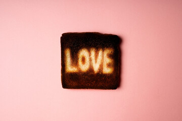 Love symbol on burnt dark slice of white bread toast with the word Love on it. creative concept...