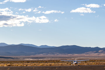 Propeller plane parked at the airport. Small airfield in front of high mountains, sunset over...