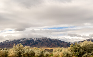 snow covered mountains in yellowstone, image shows a landscape image of the countryside, including forests at the base of the mountain and the snow covered mountain with dark clouds taken october 2023