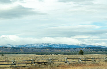 Fototapeta na wymiar snow covered mountains in yellowstone, image shows a landscape image of the countryside, including forests at the base of the mountain and the snow covered mountain with dark clouds taken october 2023