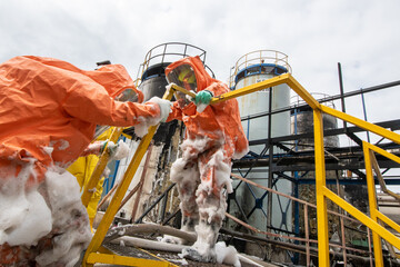 Firefighters in protective chemical suits respond to an explosion and fire of flammable liquids in...