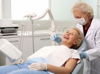 Obraz premium Elderly woman sitting in chair during the medical examination with senior female dentist in the dental office. Concept of dental care, installation of dental implants for elderly people.