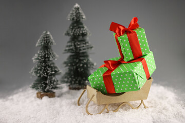 Santa Claus's sleigh in the snow. There are gifts in the sleigh. two Christmas trees next to each other