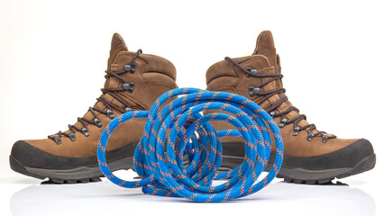 trekking boots for hiking next to a climbing rope on a white background. Travel and Hiking Equipment