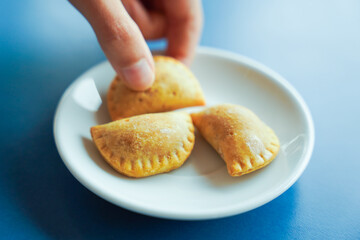 hand grabbing dumpling on plate and blue background