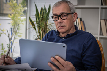 middle aged man with documents and digital tablet at workplace