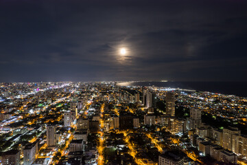 Beautiful aerial Night view of the illuminated  city of Santo Domingo - Dominican Republic with is Parks, buildings, suburbs ,turquoise Caribbean ocean, parks and malecon