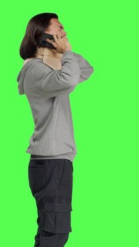 Profile of young man having neck brace makes phone call informing people about his vertebral fracture accident. Greenscreen of wounded person wearing cervical foam collar, speaking on telephone.