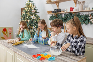 Children cooking Christmas gingerbread cookies in cozy home kitchen. Family traditions.