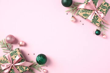 Christmas pink background with festive gift boxes, decorations, pink and green baubles on pastel pink table. Flat lay, top view.