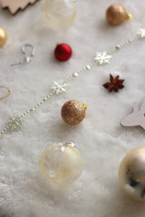 Various colorful Christmas oranments and white faux fur blanket. Selective focus.