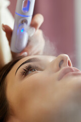 cosmetologist using primer spray for eyelash extension procedure in salon
