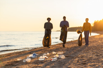 Earth day. Volunteers activists team collects garbage cleaning of beach coastal zone. Woman mans with trash in garbage bag on ocean shore. Environmental conservation coastal zone cleaning