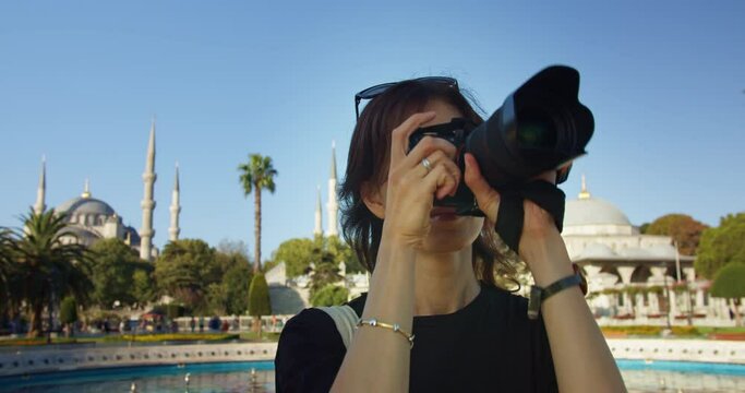 Woman take a photo on camera in front of Blue Mosque In Istanbul on a summer sunny day, female traveler taking pictures of city on summer trip