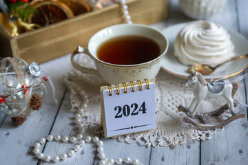 A cup of tea, New Year's toys, a calendar for the New Year 2024. Still life in vintage style.