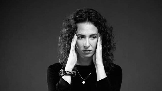 Dramatic Woman with Anxious Expression in black and white monochrome. Burnout emotion of 20s person covering face in shame and desperation