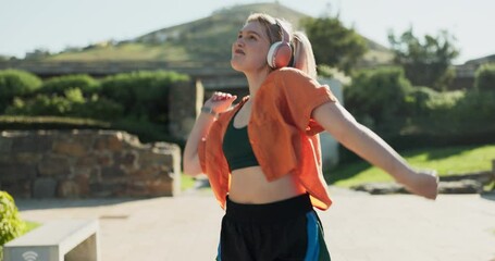 Dance, headphones and a woman walking in a garden during summer for freedom or movement in rhythm. Energy, smile or fashion with a happy young person moving to music in nature for stress relief