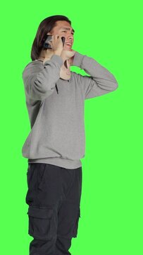 Side view of young man having neck brace makes phone call informing people about his vertebral fracture accident. Greenscreen of wounded person wearing cervical foam collar, speaking on telephone.