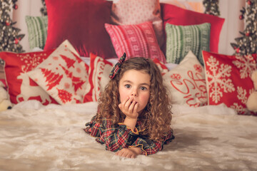 Girl lying on a carpet with a surprised face at Christmas time