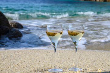 Summer time in Provence, two glasses of cold champagne cremant sparkling wine on sandy beach near Saint-Tropez in sunny day, Var department, France