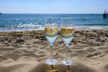 Summer time in Provence, two glasses of cold champagne cremant sparkling wine on famous Pampelonne sandy beach near Saint-Tropez in sunny day, Var department, France