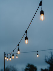 Vertical directly below shot capturing two strings of light bulbs against the backdrop of a grey,...