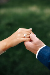 Wedding rings on hand of bride and groom on green grass background