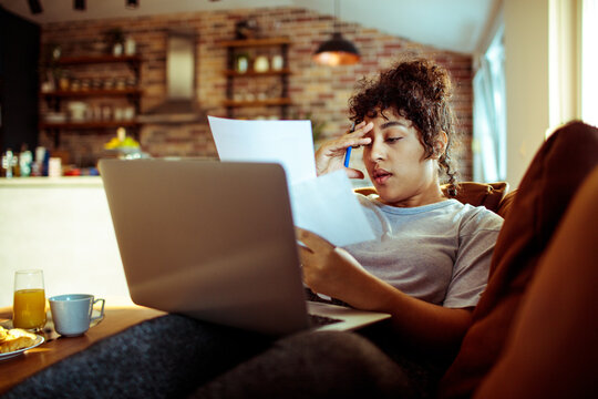 Young woman holding document with laptop at home