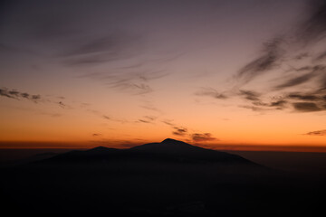 Horizontal shot with incredible colors of a sunset sky over distant silhouetted mountains.