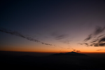 Incredible colors of captivating sunset behind the silhouetted mountain. Winter season.