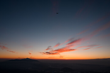 Silhouettes of mountains, low clouds and small drone at colorful sunrise in Marmarosy at winter
