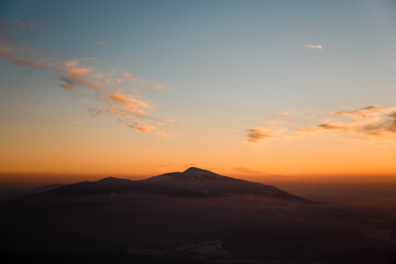 Aerial view of mountains at sunrise in winter. Mountain peak in fog.