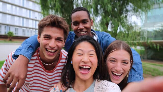 Group of young multiracial high school students talking on a video call or social media direct, waving hands, looking at camera, laughing and having fun together. Happy friendly teens shooting a photo