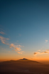 Aerial view of winter mountain peak in fog at sunrise. Beautiful landscape.