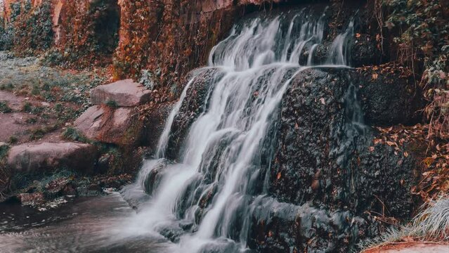 waterfall among stones and vegetation in autumn time lapse