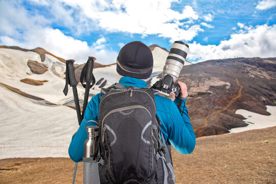male tourist photographer with a backpack looks at the beauty of nature in the mountains. nature hikes in the mountains