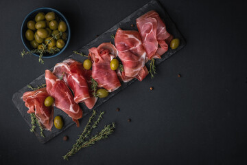 Appetizer from dry cured serrano ham or Spanish jamon iberico. Italian prosciutto crudo served with...