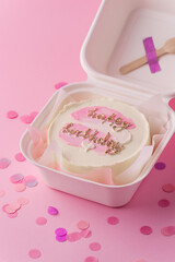 Stylish trendy Korean dessert bento cake with happy birthday inscription in the white gift box on the pink background. Small birthday cake for a girl