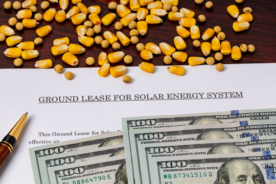 Solar energy ground lease with cash money, corn and soybeans. Solar farm contract, agriculture and renewable energy concept.
