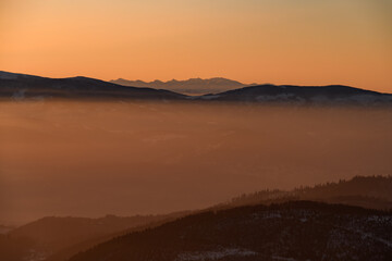 Amazing view of winter landscape with hills and mountains silhouettes during sunrise