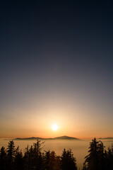 Amazing view on snow covered mountains between foggy clouds backlited with bright sun