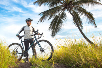Obraz premium bearded male cyclist in yellow clothes on a bicycle against the background of palm trees in nature. sports, hobbies and entertainment for health