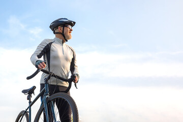 Bearded man cyclist stands with a bike against the blue sky. cycling and health hobbies