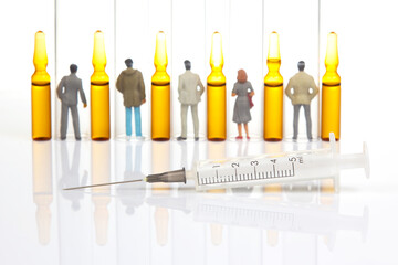 miniature people. people stand near medical ampoules and syringes. concept of vaccination and...