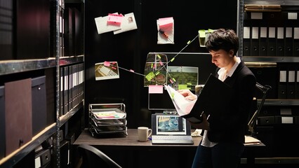 Police officer searching for evidence so solve crime case, looking at confidential records in incident room. Woman expert analyzing background check, conducting investigation with forensic reports.