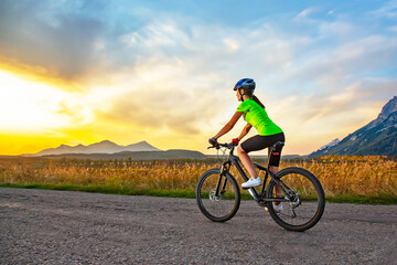Fototapeta na wymiar Beautiful woman cyclist rides a bicycle on a road. Healthy lifestyle and sports. Leisure and hobbies