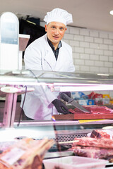 Diligent male butcher cutting big piece of beef meat in butchery