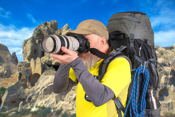 tourist photographer with a backpack photographs the beauty of nature in the mountains. nature hikes in the mountains