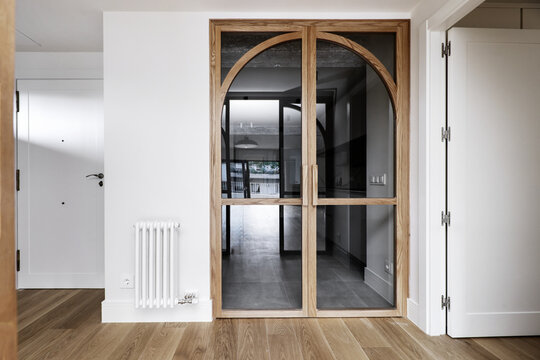 Hallway of a house with light oak wooden French doors, oak wooden floors and white painted walls