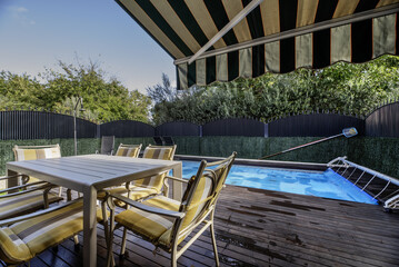 Terrace with covered pool of a single-family home with acacia wood floors, outdoor dining table...